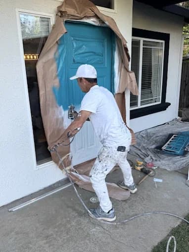 Painter spray-finishing a carefully masked front door
